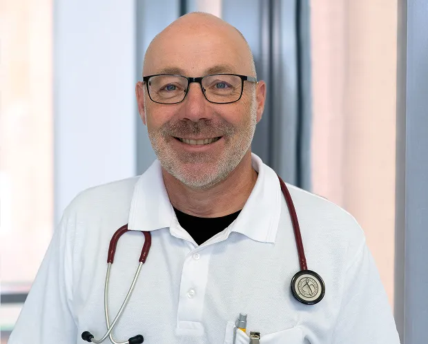 Portrait of a smiling doctor in a white shirt with a stethoscope.