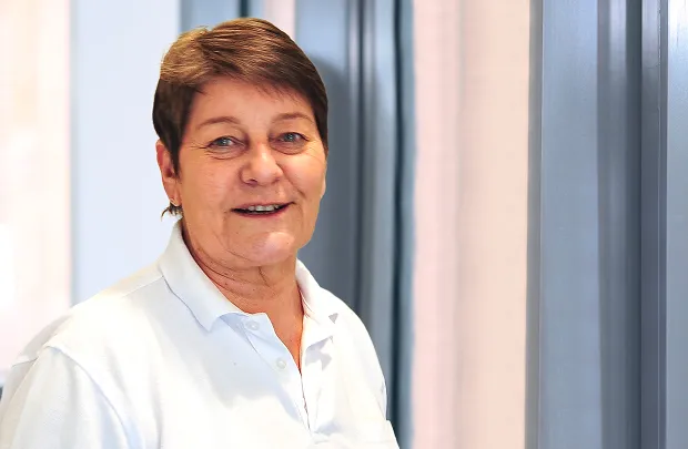 Portrait of a smiling woman with short hair against a light background.